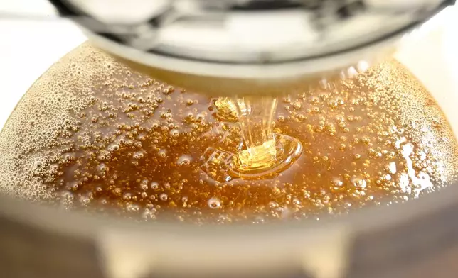 Honey is poured into a bucket in the Zografou suburb of Athens, Greece, July 1, 2025. (AP Photo/Michael Varaklas)