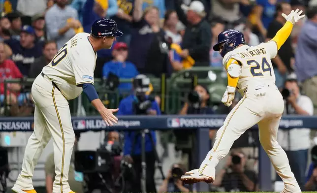 Milwaukee Brewers' William Contreras (24) celebrates with third base coach Jason Lane (40) after hitting a solo home run during the third inning of Game 2 of baseball's National League Division Series against the Chicago Cubs Monday, Oct. 6, 2025, in Milwaukee. (AP Photo/Kayla Wolf)