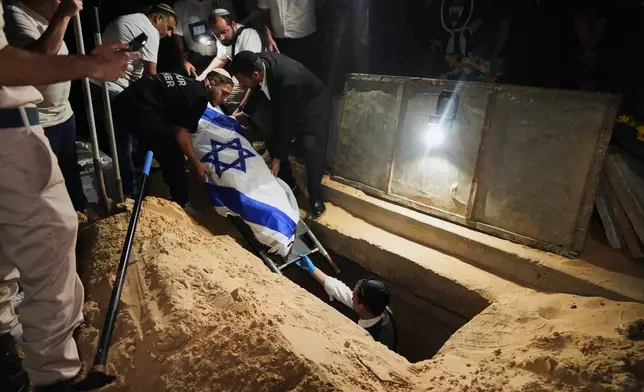 Relatives and friends lower the body of Israeli slain hostage Eitan Levi after his body was returned from Gaza as part of a ceasefire agreement between Israel and Hamas, at Bat Yam cemetery, in Holon, Israel, Thursday, Oct. 16, 2025. (AP Photo/Francisco Seco)