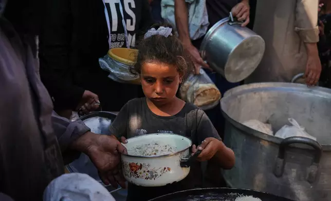 Palestinians receive donated food at a community kitchen in Deir al-Balah, central Gaza Strip, Thursday, Oct. 16, 2025. (AP Photo/Abdel Kareem Hana)