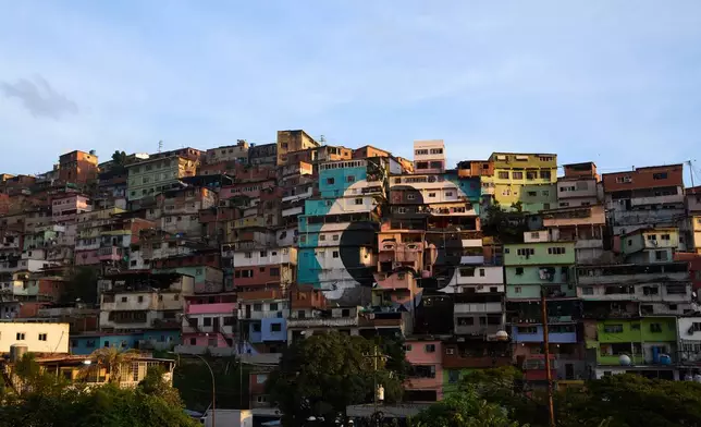 The facade of houses are emblazoned with an image of physician José Gregorio Hernandez in the neighborhood of Petare in Caracas, Venezuela, Thursday, Oct 16, 2025. Revered by millions as the “doctor of the poor”, Hernandez will be the first saint from Venezuela after Pope Francis approved a decree in February. (AP Photo/Ariana Cubillos)
