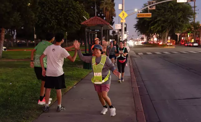 Rosa Abundiz, center, is greeted by fellow members of the Huntington Park Run Club after finishing the course in Huntington Park, Calif., Sept. 24, 2025. (AP Photo/Jae C. Hong)