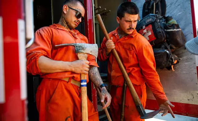 Damien Rubalcava, left, unloads tools after work at the Pine Grove Youth Conservation Camp, July 14, 2025, in Red Corral, Calif. (AP Photo/Ethan Swope)