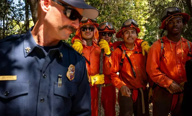 Pine Grove Youth Conservation Camp inmates pause while clearing brush along a road, July 14, 2025, near Red Corral, Calif. (AP Photo/Ethan Swope)