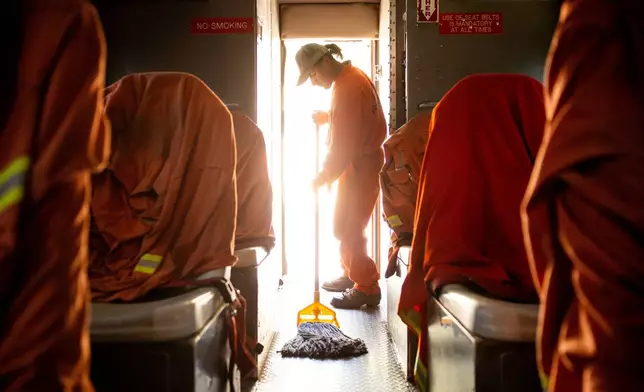 A Pine Grove Youth Conservation Camp inmate mops a crew vehicle, July 14, 2025, in Red Corral, Calif. (AP Photo/Ethan Swope)