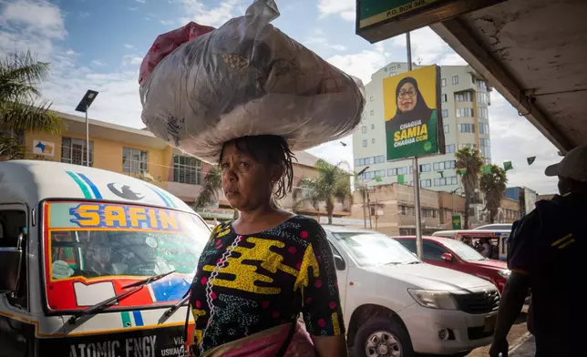 Pedestrians walk past a billboard for Tanzanian presidential candidate Samia Suluhu Hassan, of the ruling Chama Cha Mapinduzi party, in Arusha, Tanzania, Oct. 8, 2025. (AP Photo)