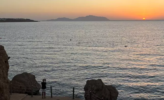 A tourist films the sunrise at the Red Sea city of Sharm el-Sheikh, Egypt, where Israeli and Hamas officials are set to hold indirect talks, on Tuesday, Oct. 7, 2025. (AP Photo)