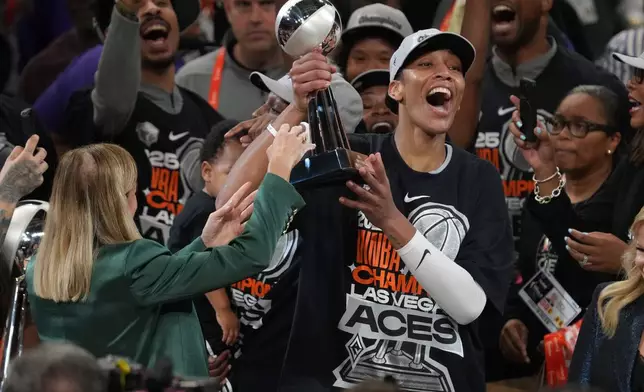 Las Vegas Aces center A'ja Wilson, center right, holds up her MVP trophy after Game 4 of the WNBA basketball finals against the Phoenix Mercury, Friday, Oct. 10, 2025, in Phoenix. (AP Photo/Rick Scuteri)