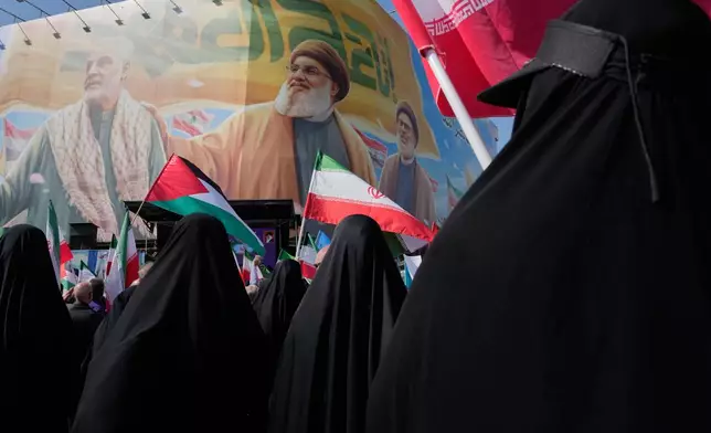Iranian worshippers wave Palestinian and Iranian flags in front of a banner showing the late commander of the Iran's Revolutionary Guard expeditionary Quds Force, Gen. Qassem Soleimani, left, and two late Hezbollah leaders Hassan Nasrallah, center, and Hashem Safieddine, during an anti-Israeli rally after the Friday prayers at the Enqelab-e-Eslami (Islamic Revolution) square, in Tehran, Iran, Friday, Oct. 10, 2025. (AP Photo/Vahid Salemi)