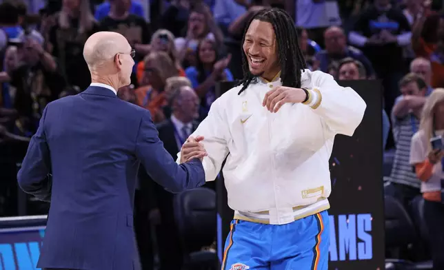 Oklahoma City Thunder forward Jaylin Williams, right, greets NBA commissioner Adam Silver during the championship ring ceremony before an NBA basketball game against the Houston Rockets, Tuesday, Oct. 21, 2025, in Oklahoma City. (AP Photo/Nate Billings)