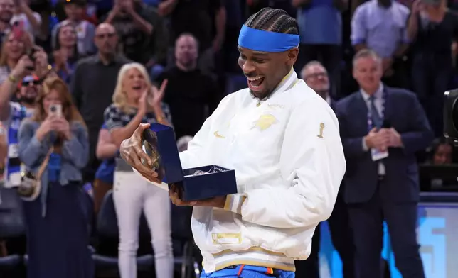 Oklahoma City Thunder guard Shai Gilgeous-Alexander looks at his championship ring during a ceremony before an NBA basketball game against the Houston Rockets Tuesday, Oct. 21, 2025, in Oklahoma City. (AP Photo/Nate Billings)