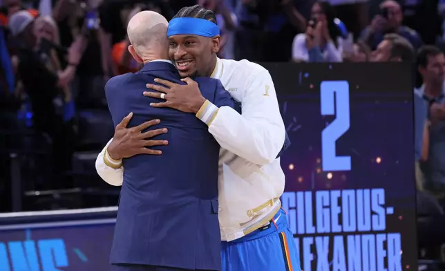 Oklahoma City Thunder guard Shai Gilgeous-Alexander, right, hugs NBA commissioner Adam Silver during the championship ring ceremony before an NBA basketball game against the Houston Rockets, Tuesday, Oct. 21, 2025, in Oklahoma City. (AP Photo/Nate Billings)