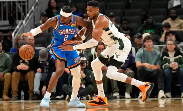 Oklahoma City Thunder guard Shai Gilgeous-Alexander (2) dribbles the ball against Milwaukee Bucks forward Giannis Antetokounmpo, right, during the first half of a preseason NBA basketball game Tuesday, Oct. 14, 2025, in Milwaukee. (AP Photo/Kayla Wolf)
