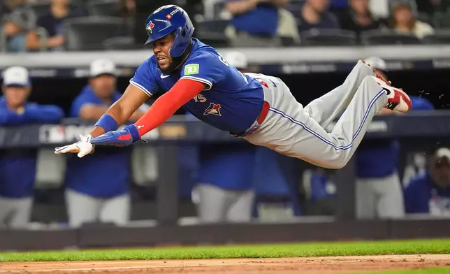 Toronto Blue Jays Vladimir Guerrero Jr. dives into home plate to score against the New York Yankees during the third inning of Game 3 of baseball's American League Division Series, Tuesday, Oct. 7, 2025, in New York. (AP Photo/Frank Franklin II)