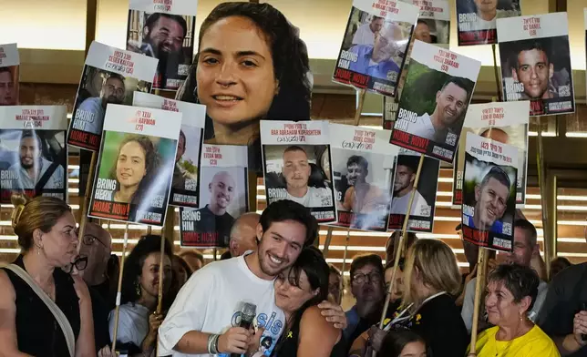 Relatives and supporters of Israeli hostages held by Hamas in the Gaza Strip hold posters with portraits of their loved ones during a gathering following the announcement that Israel and Hamas have agreed to the first phase of a peace plan to pause the fighting, at a plaza known as Hostages Square in Tel Aviv, Israel, Thursday, Oct. 9, 2025. (AP Photo/Ohad Zwigenberg)