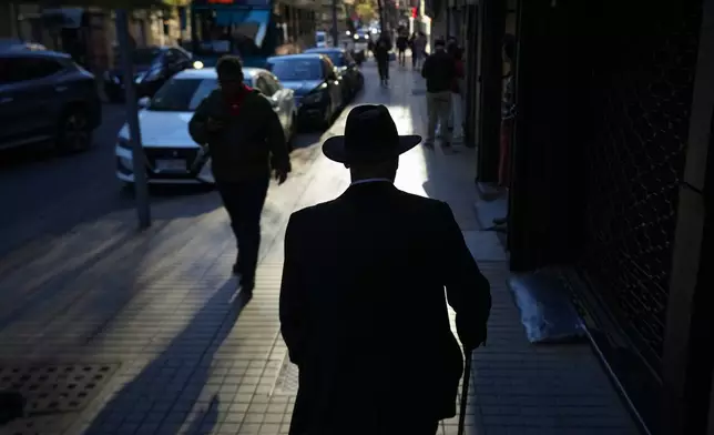 A man walks on a street in downtown Santiago, Chile, Wednesday, Oct. 1, 2025. (AP Photo/Esteban Felix)
