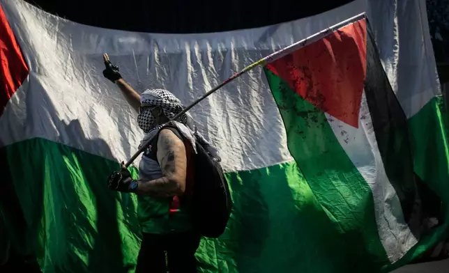 A man holds a Palestinian flag during a demonstration in solidarity with the Global Sumud Flotilla, in Rio de Janeiro, Wednesday, Oct. 2, 2025. (AP Photo/Bruna Prado)