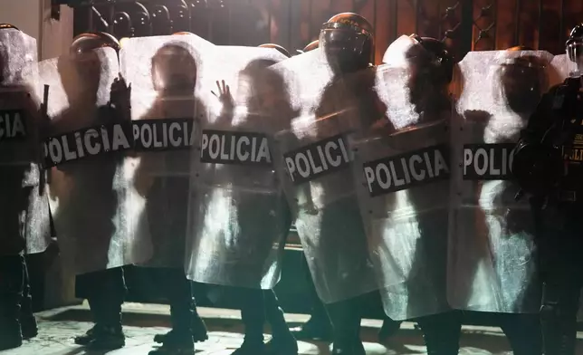 Police are silhouetted against a burning barricade as they face off with anti-government protesters during a rally against President Dina Boluarte's economic and social policies in Lima, Peru, Sunday, Sept. 28, 2025. (AP Photo/Martin Mejia)