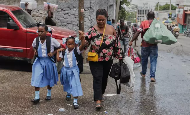 Children cross a street after school in Port-au-Prince, Haiti, Wednesday, Oct. 1, 2025. (AP Photo/Patrice Noel)