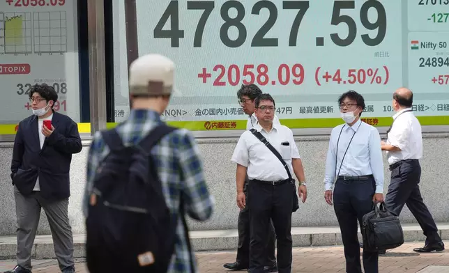 People stand in front of an electronic stock board showing Japan's Nikkei index at a securities firm Monday, Oct. 6, 2025, in Tokyo. (AP Photo/Eugene Hoshiko)