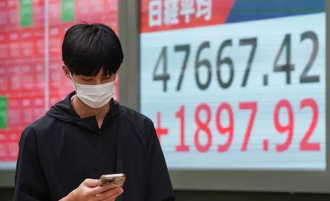 A person walks in front of an electronic stock board showing Japan's Nikkei index at a securities firm Monday, Oct. 6, 2025, in Tokyo. (AP Photo/Eugene Hoshiko)