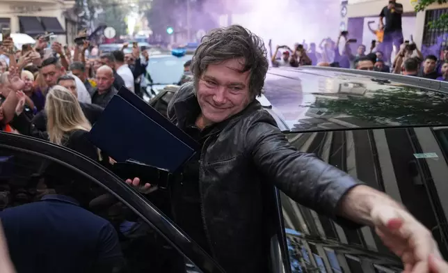 Argentine President Javier Milei waves to supporters upon arriving at a hotel in Rosario, Argentina, Thursday, Oct. 23, 2025. (AP Photo/Rodrigo Abd)