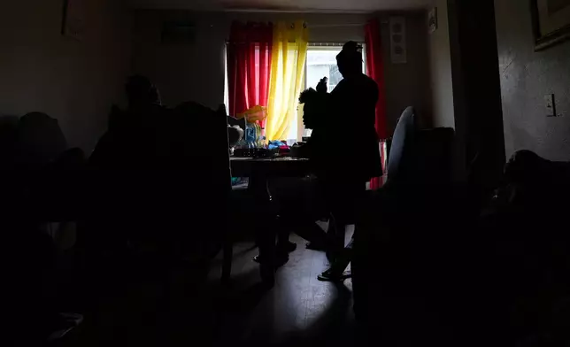 A Haitian immigrant braids another woman's hair inside a home shared by many members of a Haitian extended family, Tuesday, Aug. 19, 2025, in Orlando, Fla. (AP Photo/Rebecca Blackwell)