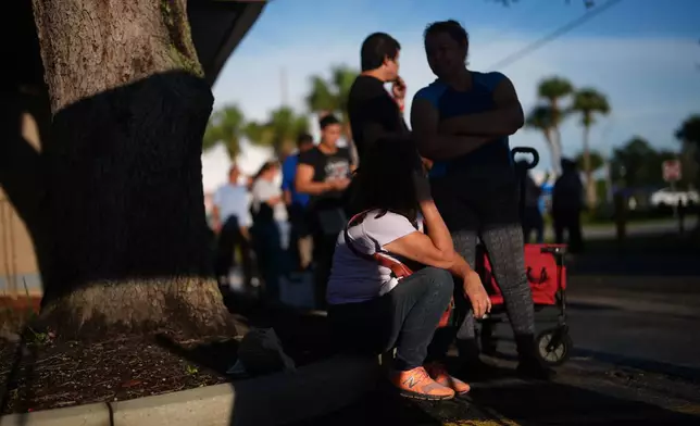 People wait in line at a food pantry that provides assistance to anyone in need, including some migrants who have had their legal protections and work permits terminated, Friday, Aug. 22, 2025, in Orlando, Fla. (AP Photo/Rebecca Blackwell)