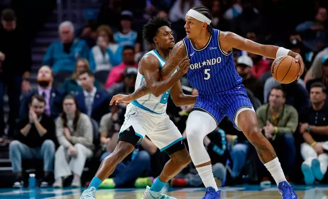 Orlando Magic forward Paolo Banchero (5) drives into Charlotte Hornets guard Collin Sexton, left, during the first half of an NBA basketball game in Charlotte, N.C., Thursday, Oct. 30, 2025. (AP Photo/Nell Redmond)