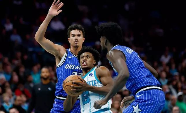Charlotte Hornets guard Collin Sexton (8) drives to the basket between Orlando Magic forwards Tristan da Silva, left, and Jonathan Isaac, right, during the first half of an NBA basketball game in Charlotte, N.C., Thursday, Oct. 30, 2025. (AP Photo/Nell Redmond)
