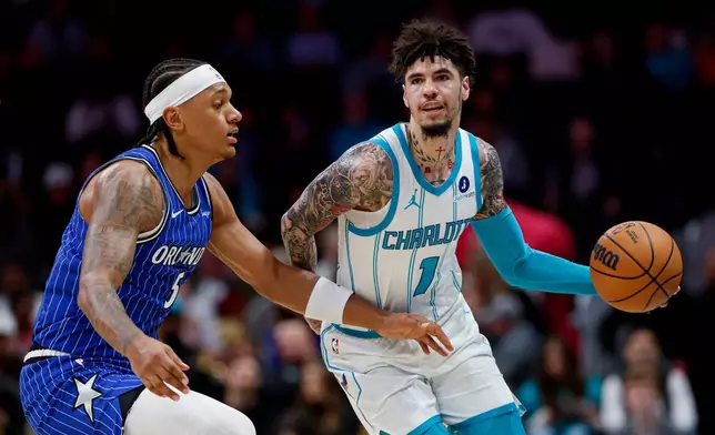 Charlotte Hornets guard LaMelo Ball (1) moves the ball against Orlando Magic forward Paolo Banchero, left, during the first half of an NBA basketball game in Charlotte, N.C., Thursday, Oct. 30, 2025. (AP Photo/Nell Redmond)