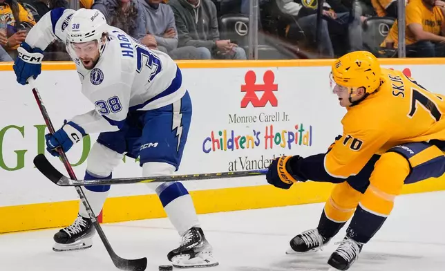 Tampa Bay Lightning left wing Brandon Hagel (38) passes the puck around Nashville Predators defenseman Brady Skjei (76) during the first period of an NHL hockey game Tuesday, Oct. 28, 2025, in Nashville, Tenn. (AP Photo/George Walker IV)