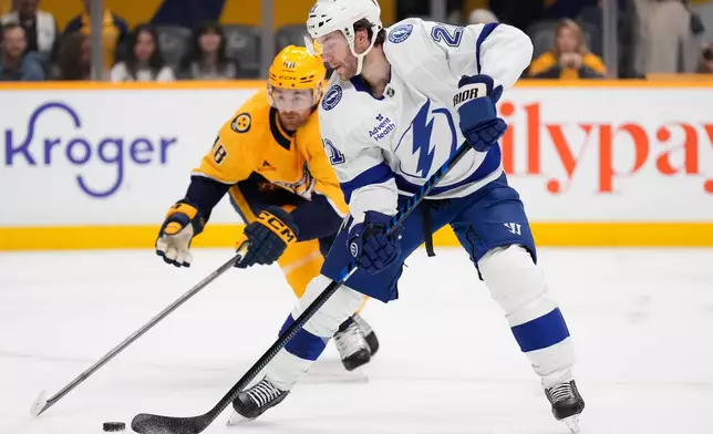 Tampa Bay Lightning center Brayden Point (21) moves the puck past Nashville Predators defenseman Nick Perbix (48) during the first period of an NHL hockey game Tuesday, Oct. 28, 2025, in Nashville, Tenn. (AP Photo/George Walker IV)