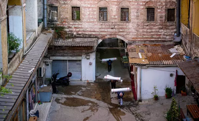 Porters carry loads on their backs inside the historic Büyük Yeni Han commercial building in Istanbul, Turkey, Wednesday, Sept. 24, 2025. (AP Photo/Emrah Gurel)