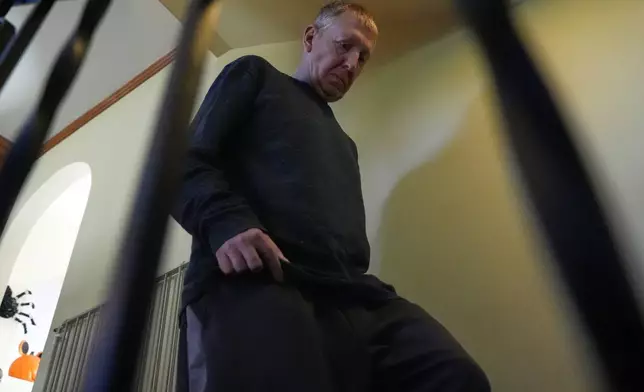 Bill Swick walks down stairs to study with his wife Martha Swick at his home in Minooka, Ill., Friday, Oct. 24, 2025. (AP Photo/Nam Y. Huh)