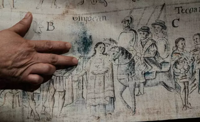 Areli Ortiz, technical deputy director of the National Institute of Anthropology and History, points to depictions on fabric of La Malinche and Hernan Cortes from a facsimile of part of the 16th century Tlaxcala Codex in Mexico City, Wednesday, Oct. 8, 2025. (AP Photo/Marco Ugarte)