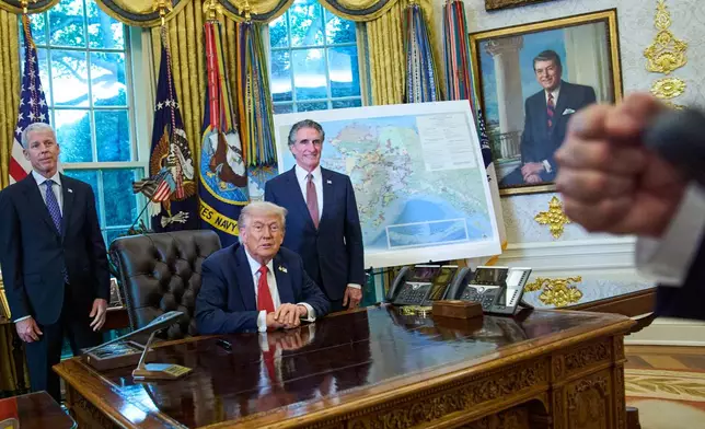 President Donald Trump congratulates a reporter on how young he looks, during an executive order signing in the Oval Office at the White House, Monday, Oct. 6, 2025, in Washington, as Energy Secretary Chris Wright, left, and Interior Secretary Doug Burgum listen. (AP Photo/Jacquelyn Martin)