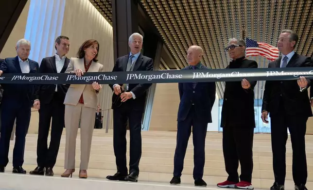 JPMorgan Chase CEO Jamie Dimon, fourth from left, prepares to cut the ribbon on a new JPMorgan Chase building during a ceremony in New York, Tuesday, Oct. 21, 2025. Also holding the ribbon, from left to right: Jerry Speyer, Rob Speyer, NY Governor Kathy Hochul, Dimon, Norman Foster, Deepak Chopra and David Arena. (AP Photo/Seth Wenig)