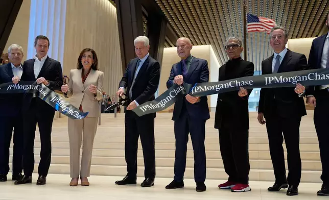 JPMorgan Chase CEO Jamie Dimon, fourth from left, cuts the ribbon on a new JPMorgan Chase building during a ceremony in New York, Tuesday, Oct. 21, 2025. Also holding the ribbon, from left to right: Jerry Speyer, Rob Speyer, NY Governor Kathy Hochul, Dimon, Norman Foster, Deepak Chopra and David Arena. (AP Photo/Seth Wenig)