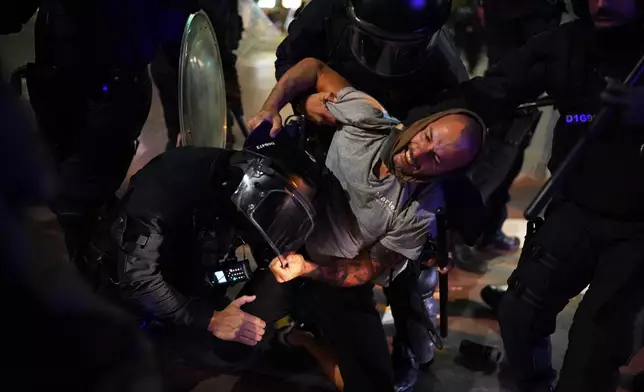 A demonstrator scuffles with police during a protest in support of Palestinians and protesting Israel's actions, in Barcelona, Spain, Wednesday, Oct. 15, 2025. (AP Photo/Joan Mateu Parra)