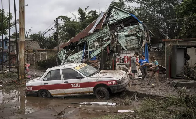 Neighbors gather around a damaged house after heavy rainfall in Poza Rica, Veracruz state, Mexico, Saturday, Oct. 11, 2025. (AP Photo/Felix Marquez)