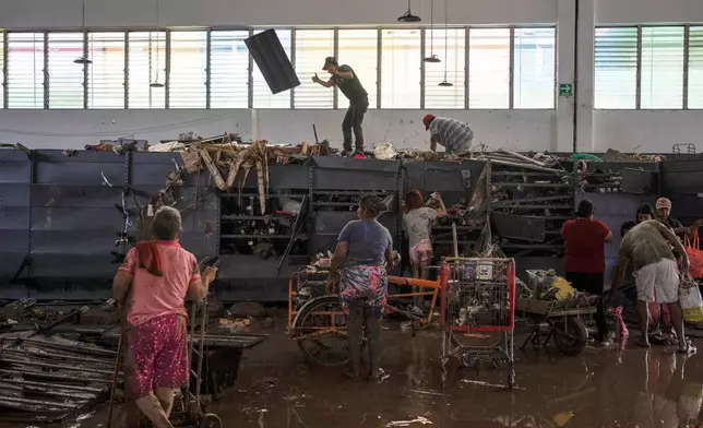 People loot a supermarket damaged by heavy rainfall in Poza Rica, Veracruz state, Mexico, Saturday, Oct. 11, 2025. (AP Photo/Felix Marquez)