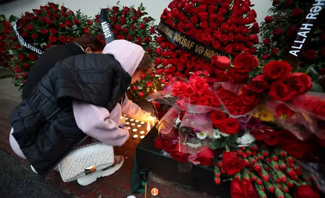 FILE - A woman lights candles at the wall of the apartment building in Baku, Azerbaijan, Dec. 28, 2024, in memory of pilot Alexander Kalyanin, who died in the crash of an Azerbaijan Airlines jet near the Aktau, Kazakhstan, airport. (AP Photo, File)
