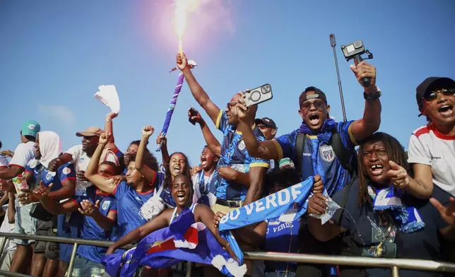 Fans celebrate in the stands after Cape Verde defeated Eswatini in a World Cup qualifying soccer match at Estádio Nacional in Praia, Cape Verde, Monday, Oct. 13, 2025, to clinch their qualification for the 2026 World Cup. (AP Photo/Cristiano Barbosa)