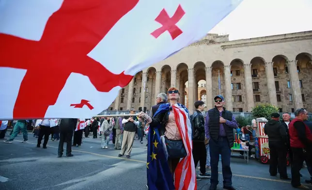 Opposition supporters with Georgian national and a U.S. national flags gather in the city center of Tbilisi, Georgia, on Saturday, Oct. 4, 2025, boycotting the municipal elections and call for the release of political opponents. (AP Photo/Zurab Tsertsvadze)