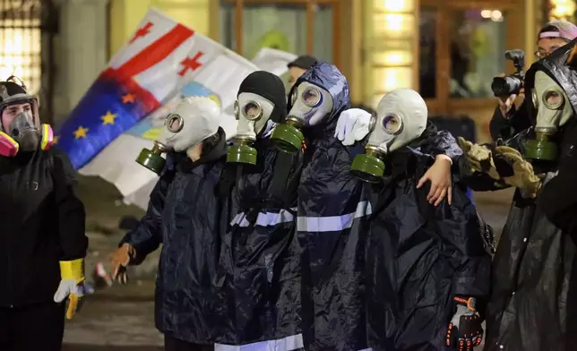 Protesters in gas masks stand in front of police during an opposition rally in the city center of Tbilisi, Georgia, on Saturday, Oct. 4, 2025, boycotting the municipal elections and call for the release of political opponents. (AP Photo/Zurab Tsertsvadze)