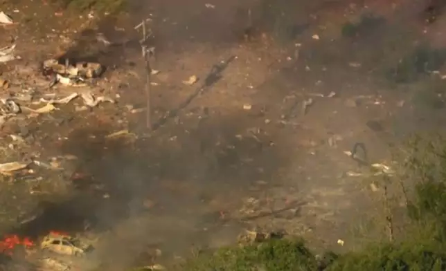Smoke fills the air as debris covers the ground and vehicles after a powerful blast ripped through a military explosives manufacturing plant in Hickman County, Tenn., on Friday, Oct. 10, 2025. (WTVF-TV via AP)