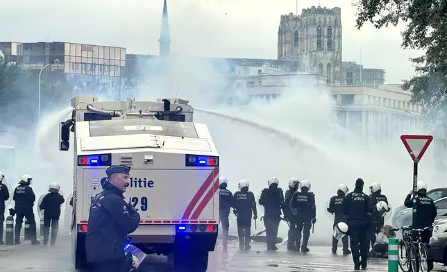 Police use a water cannon against protestors during a demonstration and general strike in Brussels, Tuesday, Oct. 14, 2025. (AP Photo/Sylvain Plazy)
