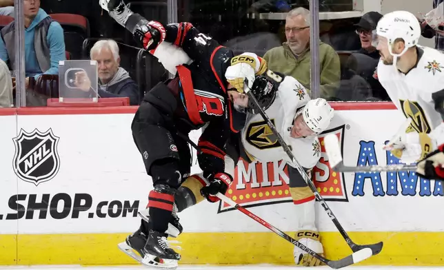 Carolina Hurricanes center Seth Jarvis (24) and Vegas Golden Knights defenseman Brayden McNabb (3) collide along the boards during the first period of an NHL hockey game Tuesday, Oct. 28, 2025, in Raleigh, N.C. (AP Photo/Chris Seward)