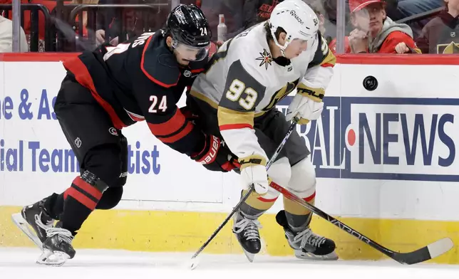 Carolina Hurricanes center Seth Jarvis (24) and Vegas Golden Knights right wing Mitch Marner (93) go for the puck during the first period of an NHL hockey game Tuesday, Oct. 28, 2025, in Raleigh, N.C. (AP Photo/Chris Seward)